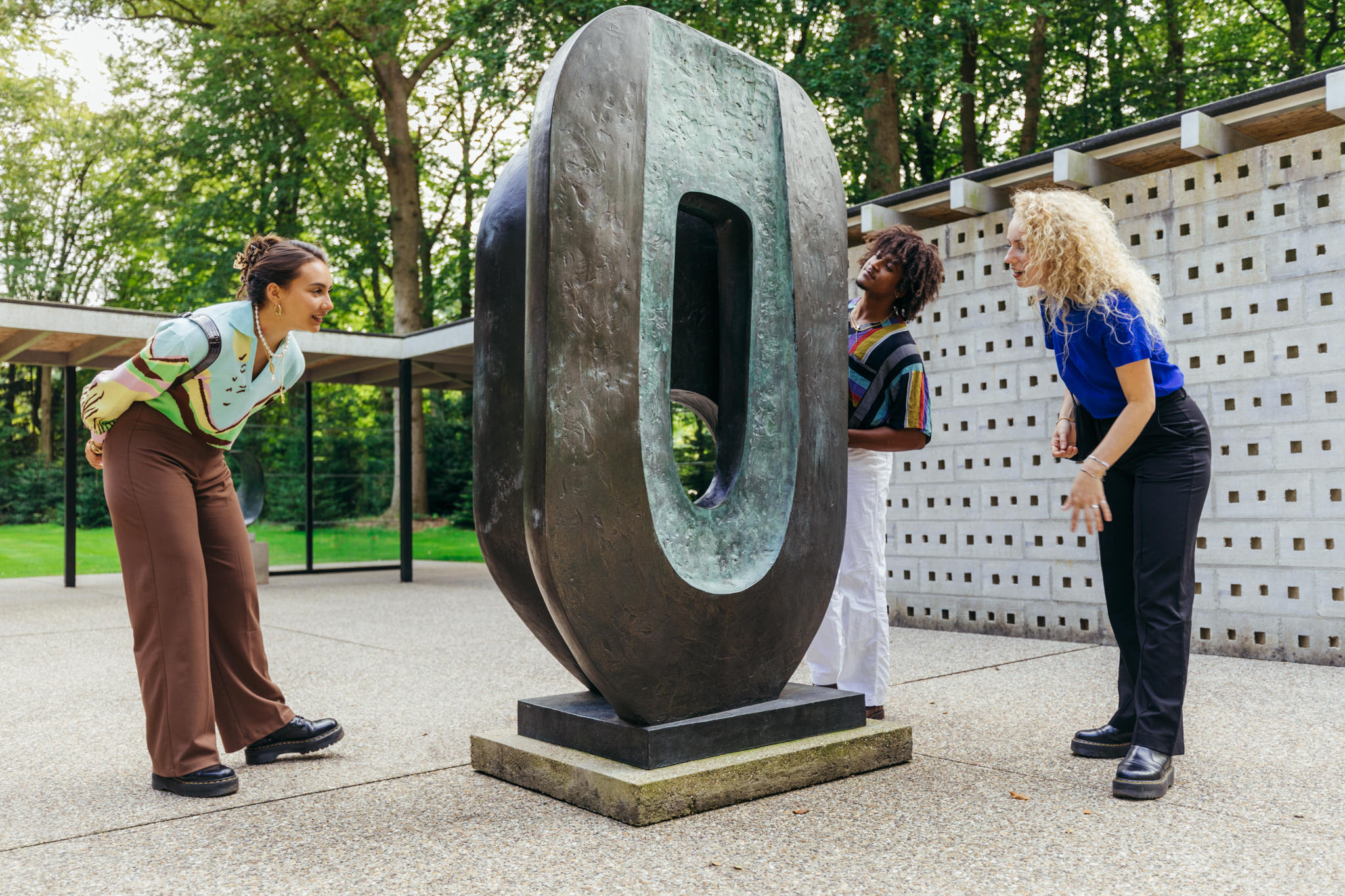 Drei Besucher im Rietveld Pavillion neben einem Kunstwerk von Barbara Hepworth